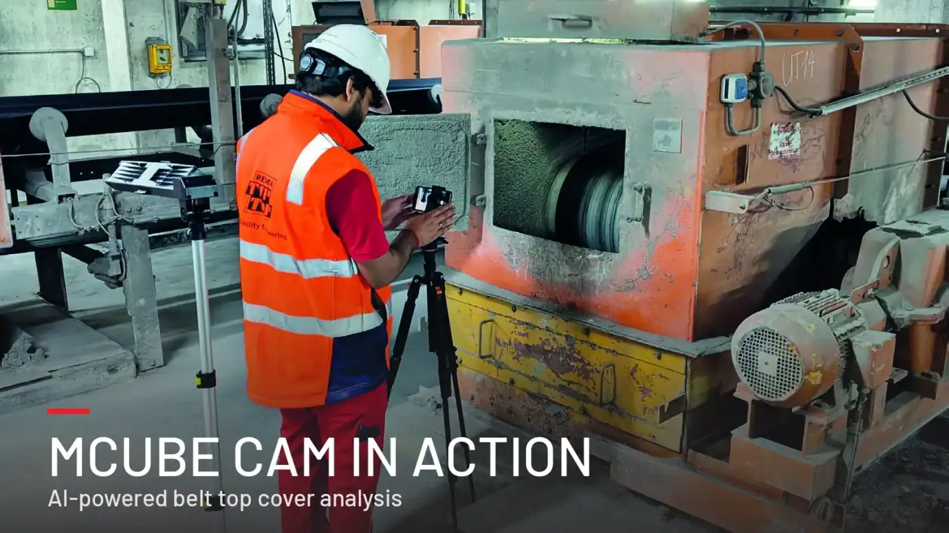 REMA TIP TOP technician filming a conveyor belt through an inspection hatch with a smartphone on a tripod for MCube CAM analysis